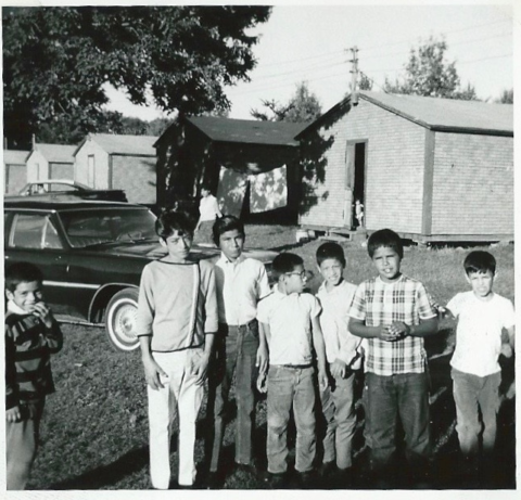 a black and white photo showing a group of children in front of cabins