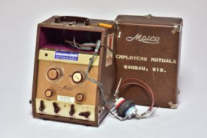 Color photograph of a audiometer, which looks a bit like a box with knobs and wires coming out of it.