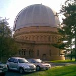 A color image showing the exterior of the Yerkes Observatory with cars in the foreground