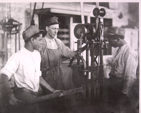 An image of a teacher and two teenaged boys working in a metalsmithing shop at the Illinois State Reformatory in 1938.