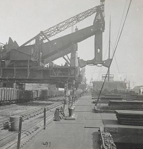 A view of the docks showing a Hullet mechanical loader, which looks like a crane with two buckets on the end of its neck.
