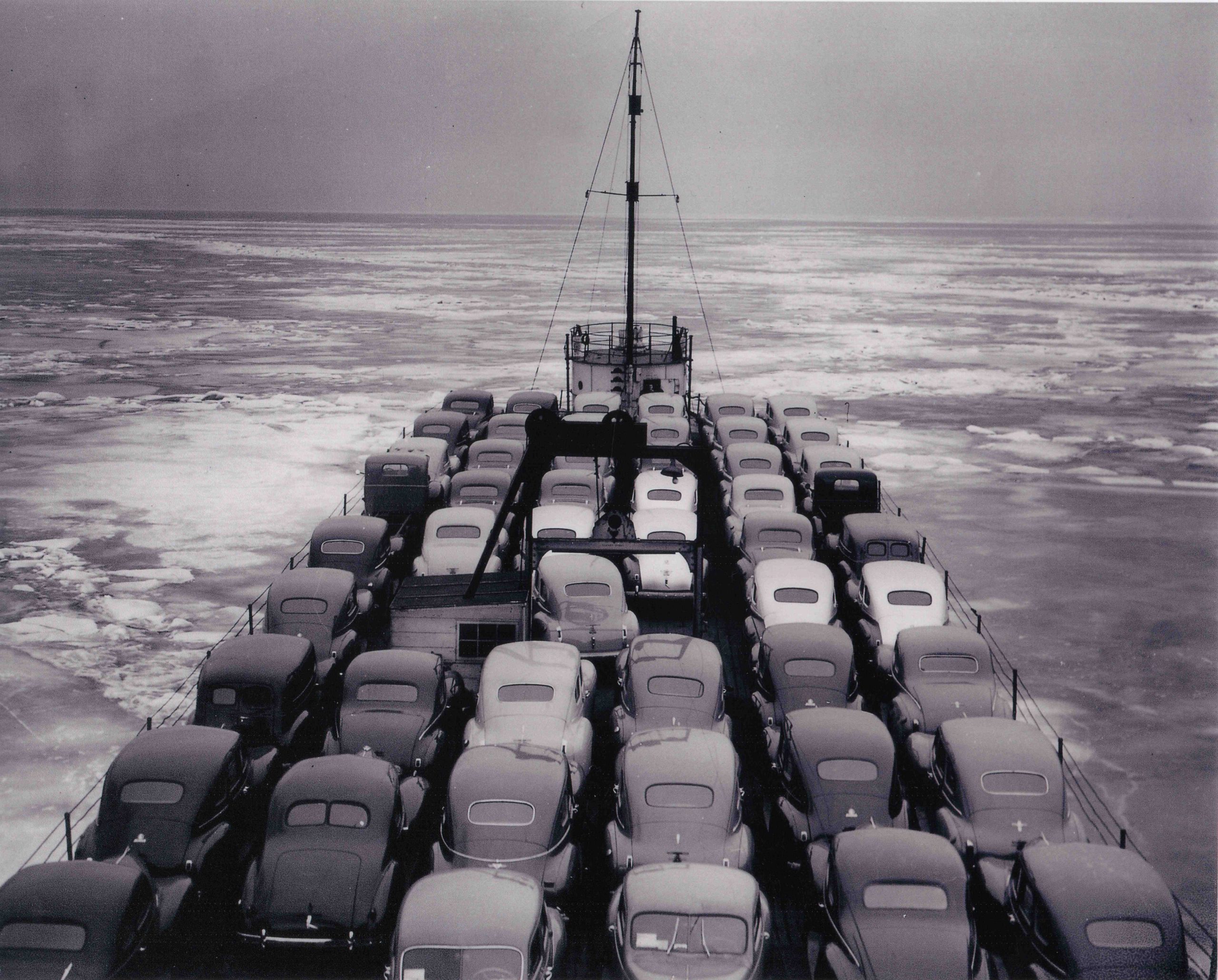 A black and white image showing lines cars lined up across the deck of a whaleback ship.