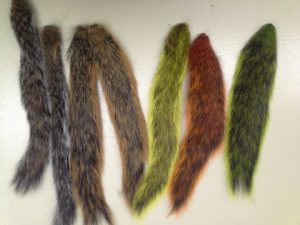 a color photo showing seven squirrel tails, several of them dyed different colors like red, yellow or green