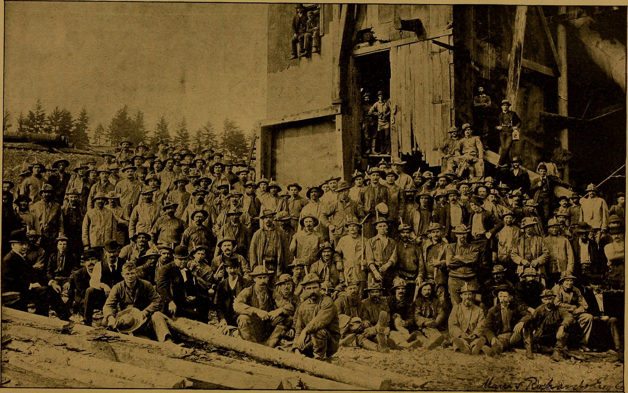 A faded group photograph of miners in the Memominee Iron Range