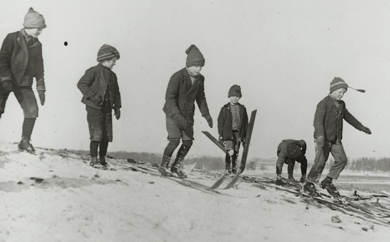 Six boys practice on skiis in this black and white photo