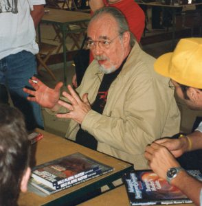A portrait of Gary Gygax at a convention speaking with D&D players