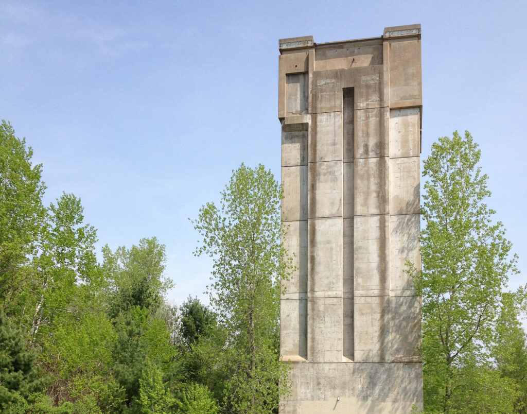 A picture of the Kickapoo Valley Reserve dam tower showing a concrete tower rising nearly 100 feet above a grassy lawn
