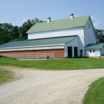 A color photo of a large white barn built into an embankment