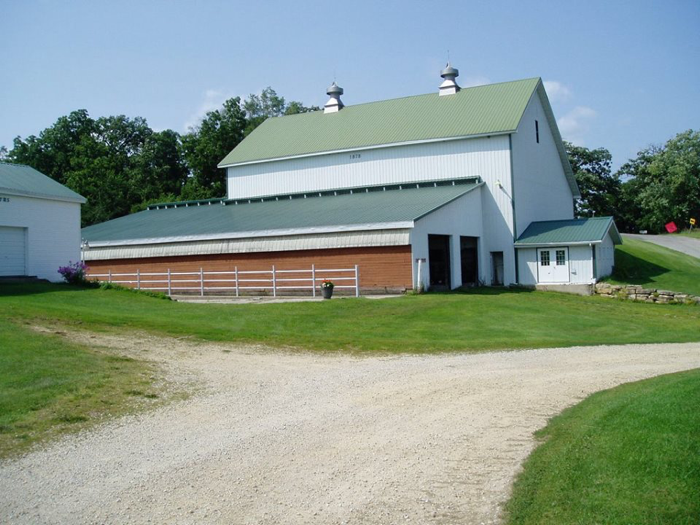 A color photo of a large white barn built into an embankment