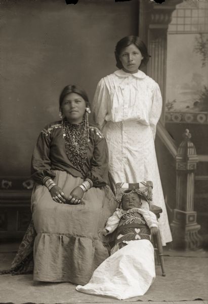 two Ho-Chunk women pose with a baby in a cradleboard