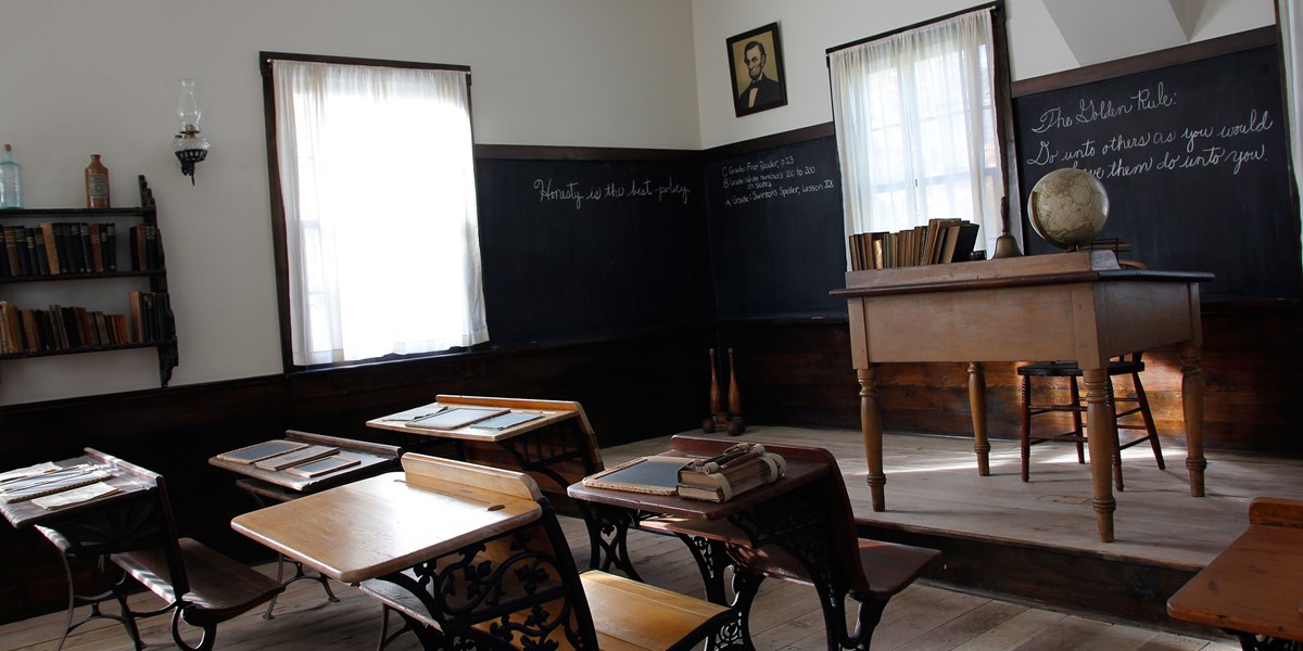 The interior of a one room school house showing exercises on the blackboard