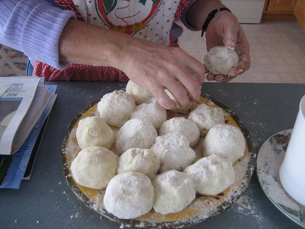 A woman dividing dough before making lefse
