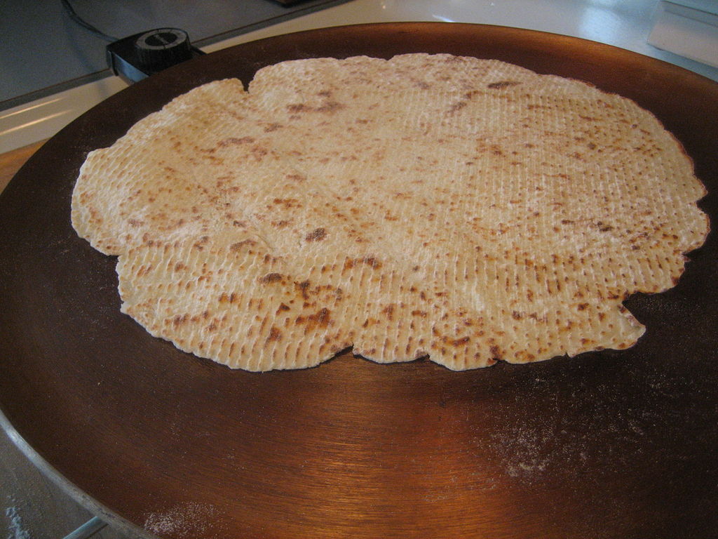Lefse rolled thin and cooking on a griddle
