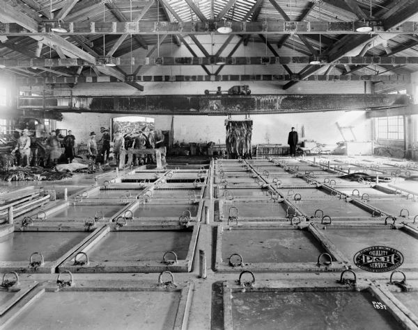 A black and white image of a long room filled with square pits in the floor filled with grey water