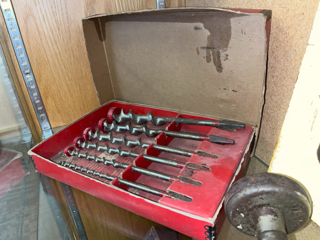 Box of drill bits from Slaske's tool set, in the iconic red box, this is likely a Craftsman Auger Bit Set, No. 9-4156. From the collection of the Greendale Historical Society.