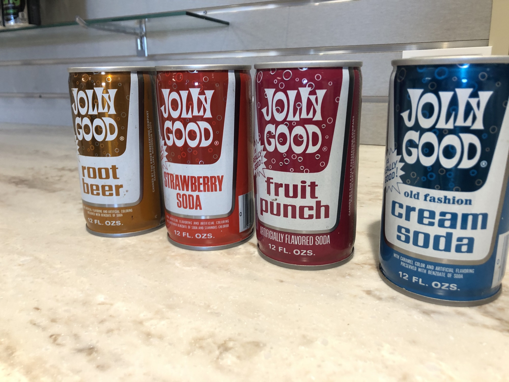 Four Jolly Good soda cans in a line.
