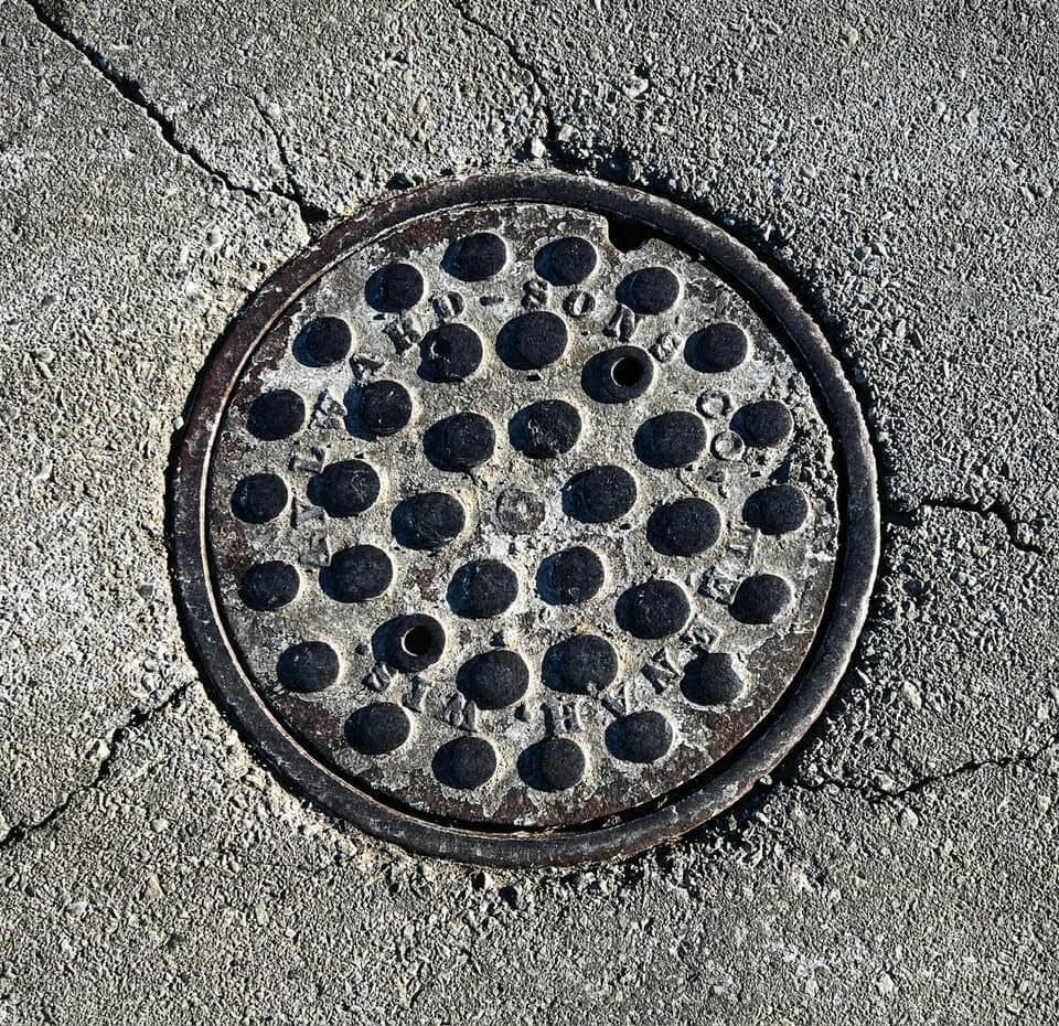 Manhole cover with raised dot design, in relief lettering it reads, "Aylward-Sons Co. Neenah, Wis."