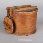 A wooden drum with lid and crank wheel.
