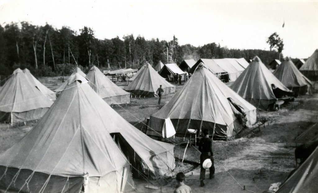 Photograph of a camp village with large canvas tents.