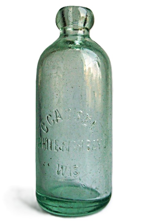 A green glass bottle with molded relief lettering that reads, “C CASSEL WHITE FISH BAY WIS”