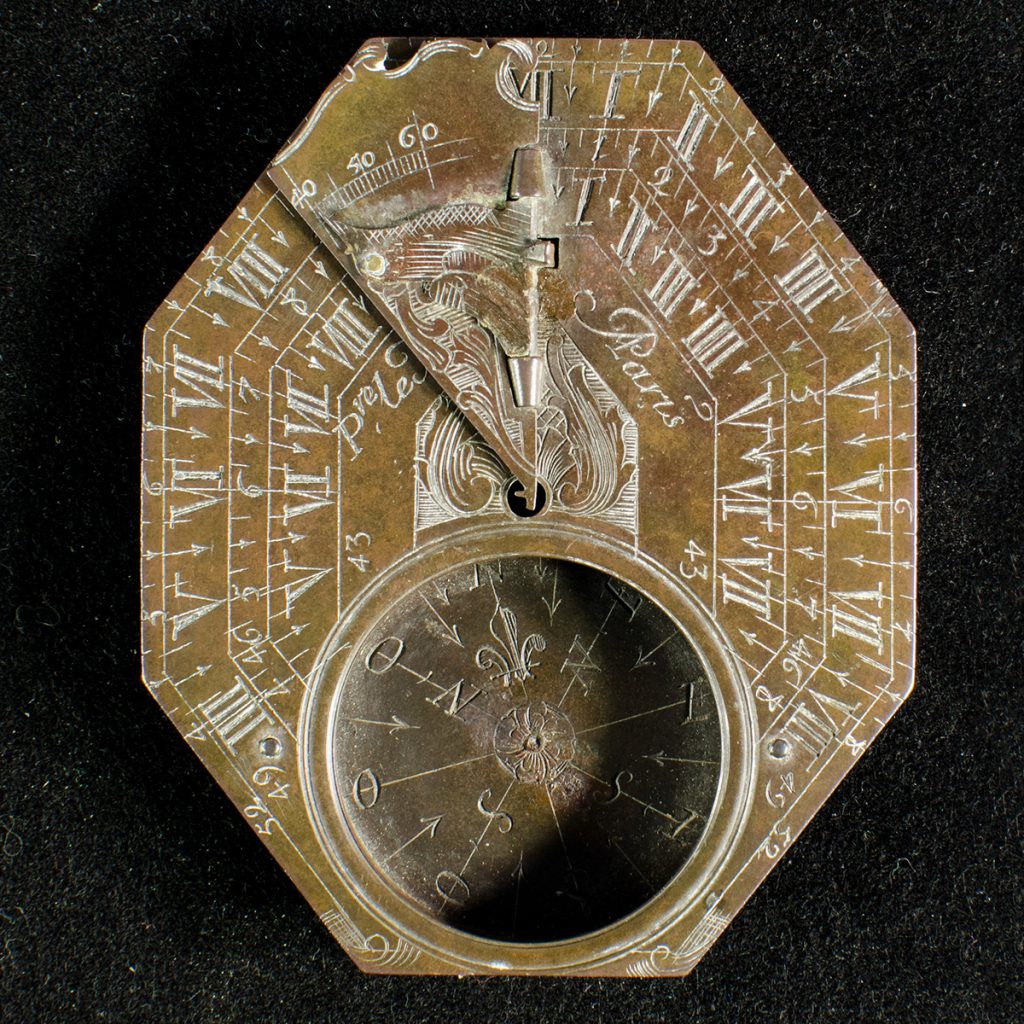 An octagonal, engraved brass sundial and compass.