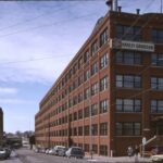 Photograph of the first Harley-Davidson factory, a five-story brick factory building.