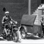 Photograph of two men posed on motorcycles with trunk-style sidecars labeled 'The Milwaukee Journal'