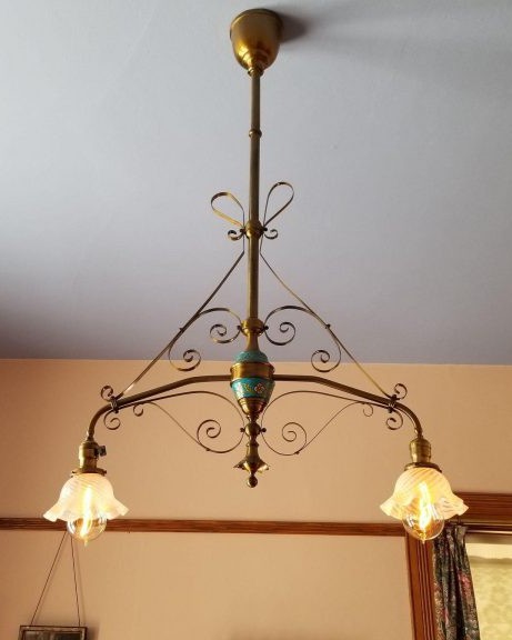A brass chandelier with wrought brass-work and two lamps with glass diffusers.