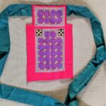 Photo of a baby pink baby carrier adorned with purple, black, and yellow embroidery and applique; and teal ribbon ties.