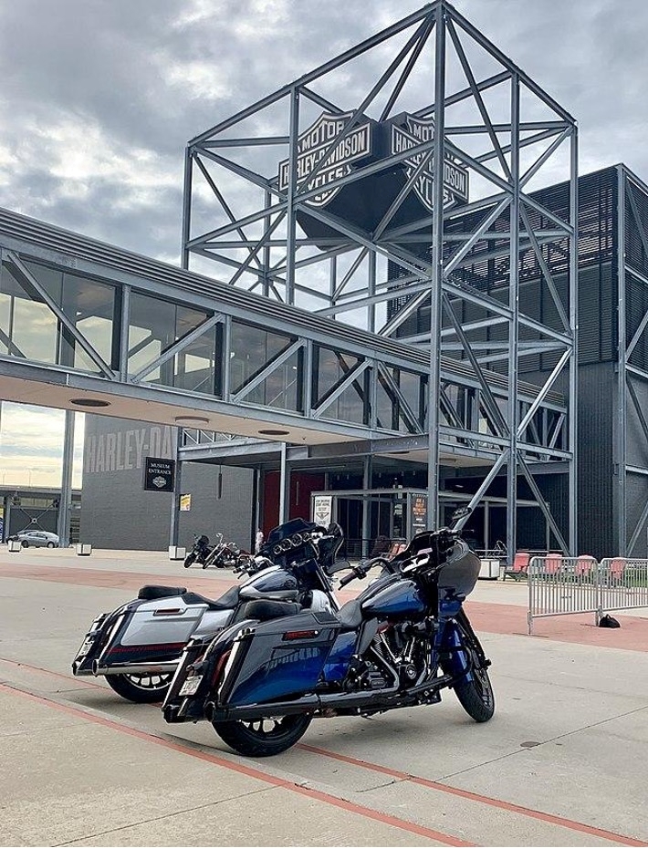 Two motorcycles parked in front of a industrial-style museum building.