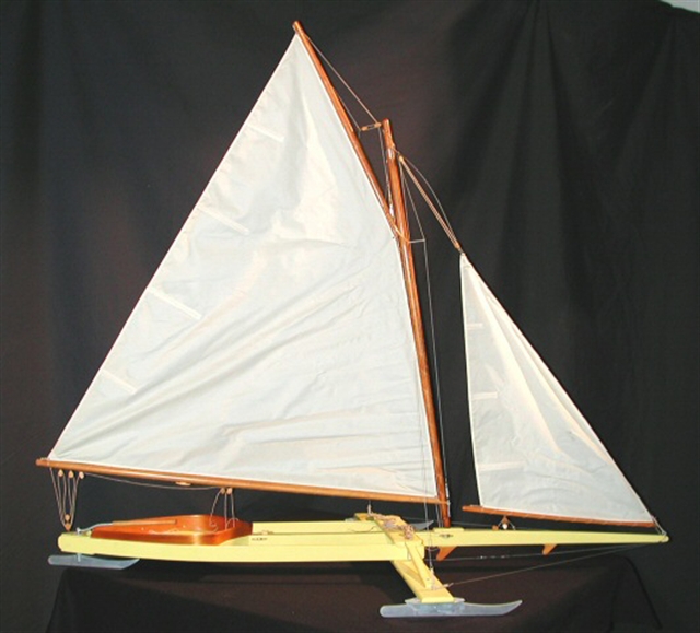 A model of a Madison-style ice boat. The hull is shallow with runners extending on either side, and the boat has a mast with two sails.