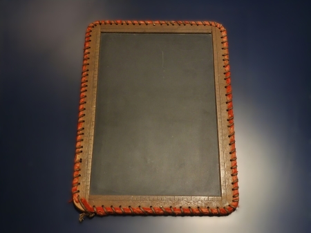 Image of a slate tablet with wooden ruled edges bound with leather.