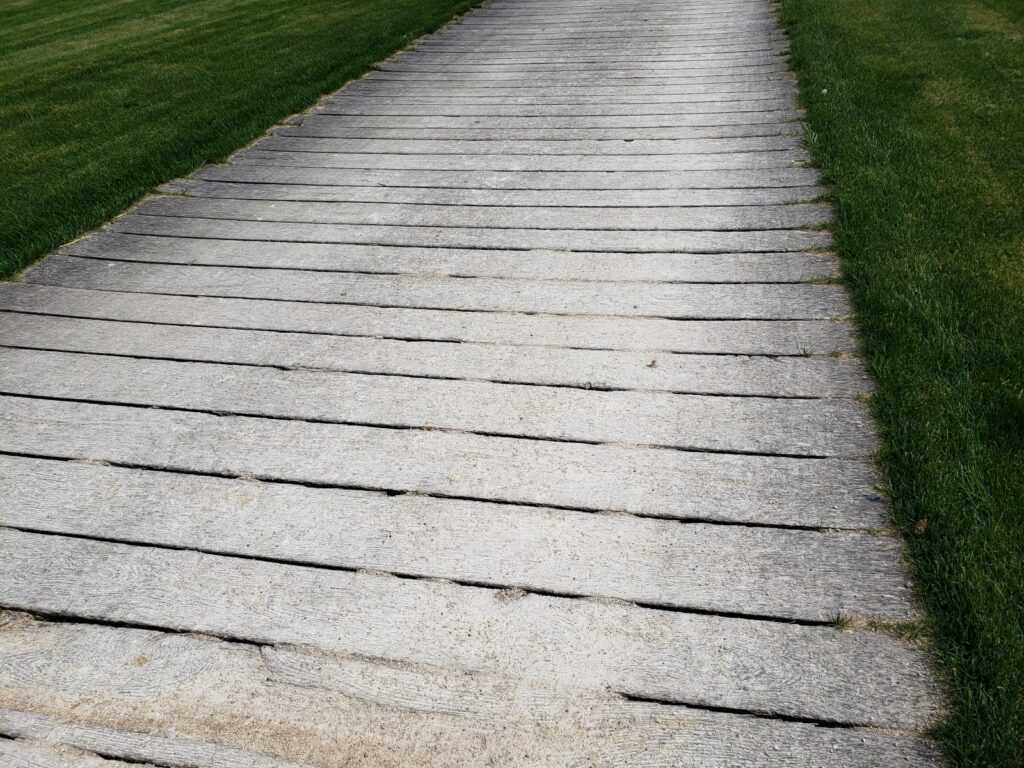 A wooden plank road on a grassy landscape.