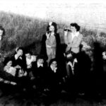 A newspaper clipping showing a group for eleven women gathered for a picnic on a beach.