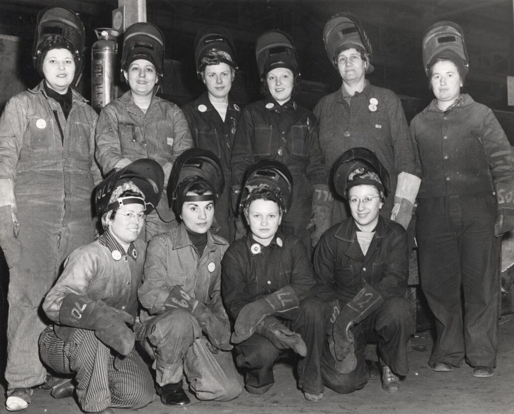 A group of women in welding uniforms pose for the camera.