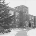 A grand brick campus building with a central tower.