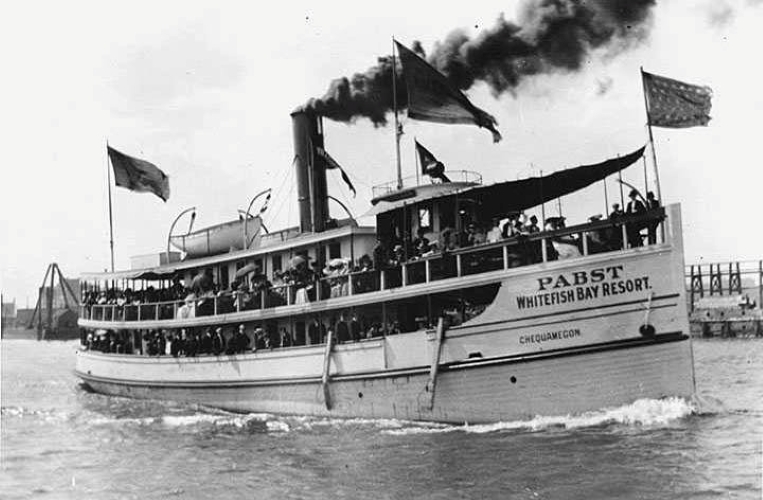 Passengers aboard a two-level steamboat. The bow reads “Pabst Whitefish Bay Resort”