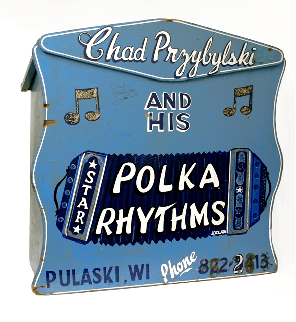 A blue bandstand sign that features a hand-painted image of an accordion and music notes, and that reads "Chad Przybylski and his Polka Rhythms"