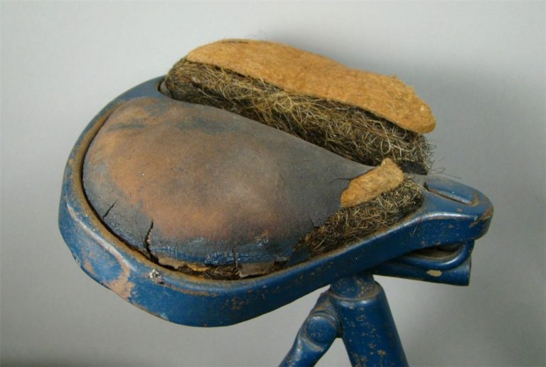 A detail image of the bicycle showing the seat. Part of the leather is missing revealing the hair and cotton stuffing inside.