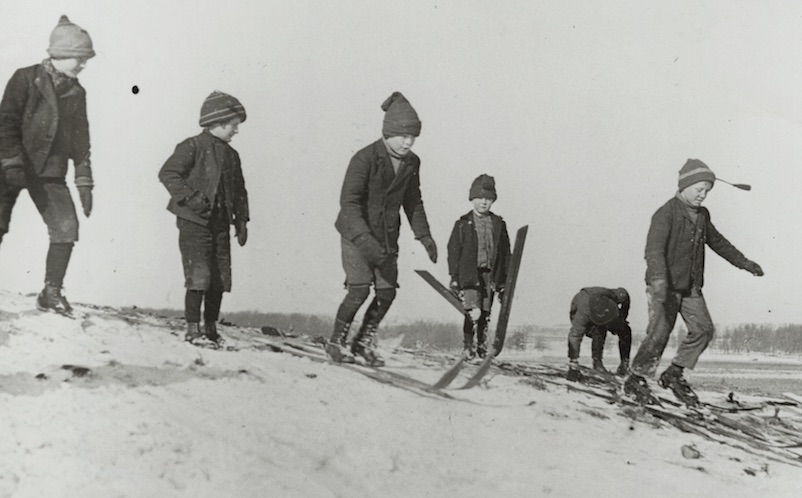 Winter scene with boys on skis preparing to compete at the first ski tournament in Stoughton, Wisconsin, possibly in ski jumping.