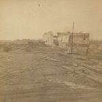 Photograph showing a burned landscape and the hollowed ruins of a building.