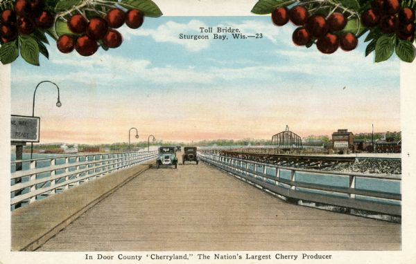 A color postcard of two automobiles crossing a toll bridge. There are cherries on branches at the top of the postcard. Caption reads: "In Door County 'Cherryland,' The Nation's Largest Cherry Producer."