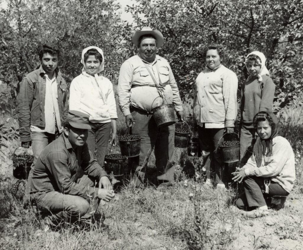 A family of migrant workers pose in front of an orchard.