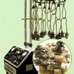 Permanent wave machine. Mechanical box on a stand with tubes extending from the top to connect to a halo with curlers. Inset shows curlers in a model's hair.