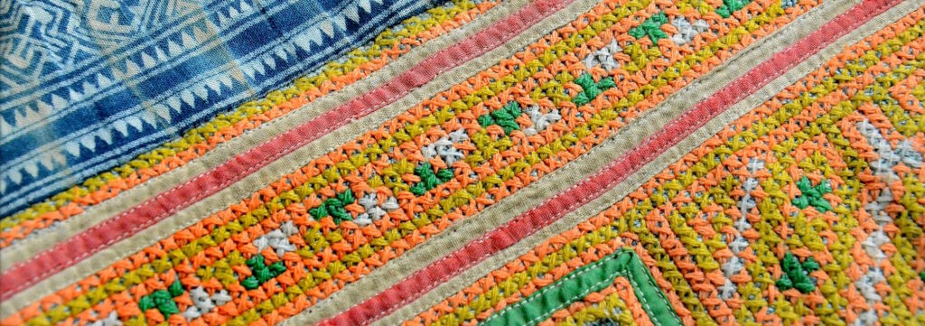 A detail of a section of Hmong embroidery showing cross-stitch pattern, batik, and applique work.