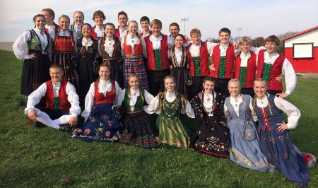 A posed photograph of the 2014 Stoughton Norwegian Dancers. They're dressed in traditional Norwegian costume.