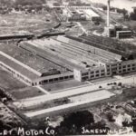 Photograph postcard with an aerial view of a large factory.