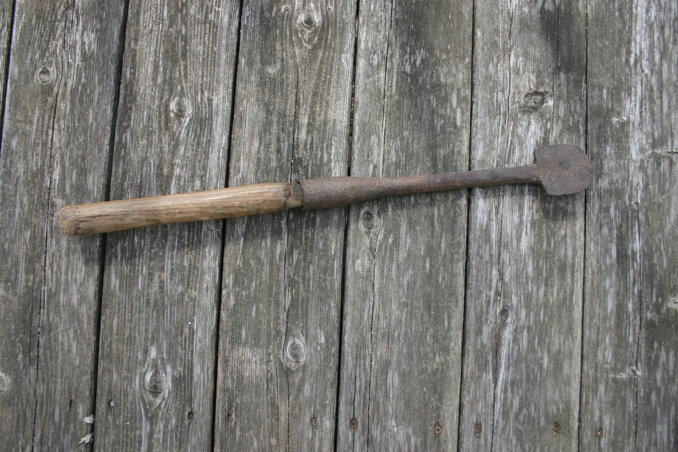 Photograph of a bark spud. A spade-shaped tool with long wooden handle.