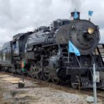 Photograph of a steam train engine on a rail road.