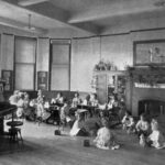 Image of several children sitting before a fireplace playing with toys.
